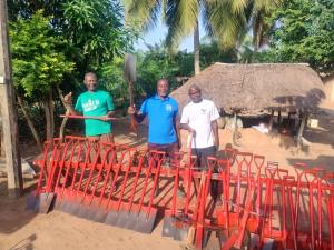three men stand behind a long line of shovels that are spread out in display