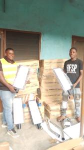 two men stand in front of the stack of boxes of light bulbs